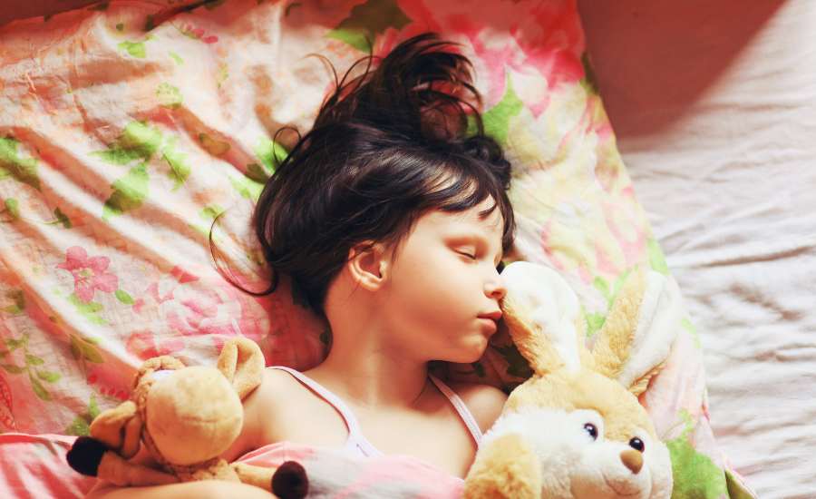 Une fillette brune dort le nez sur son doudou, rassurée par son odeur
